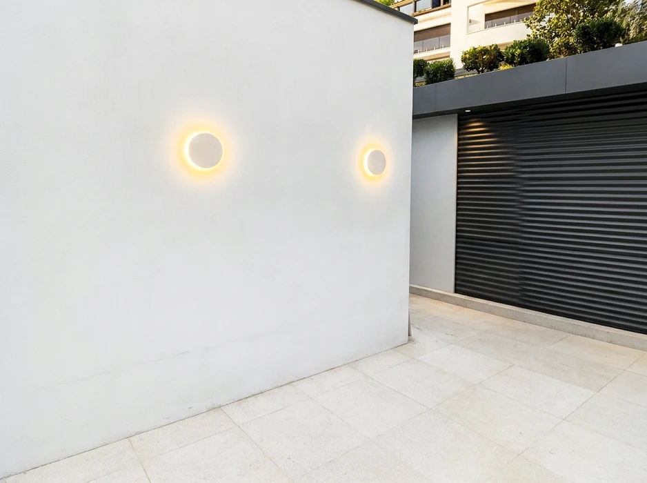 Façade extérieure blanche avec deux appliques murales rondes type halo LED à lumière chaude, montées en symétrie