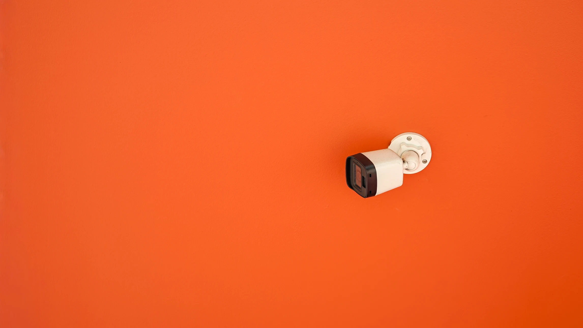 Caméra de surveillance extérieure installée dans un environnement résidentiel avec végétation luxuriante et bâtiments en arrière-plan