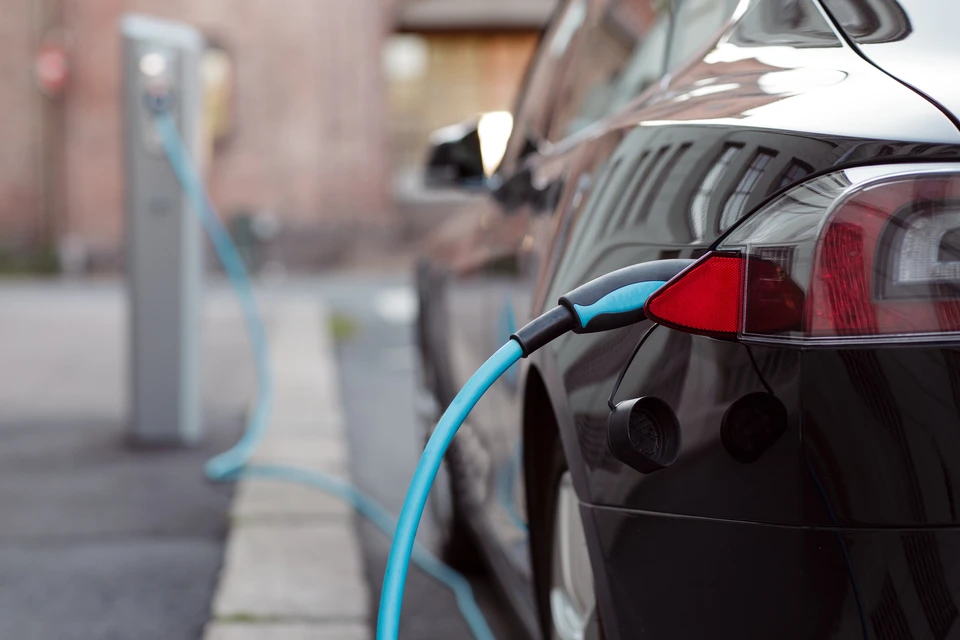 Scène extérieure urbaine montrant une voiture électrique noire en cours de recharge